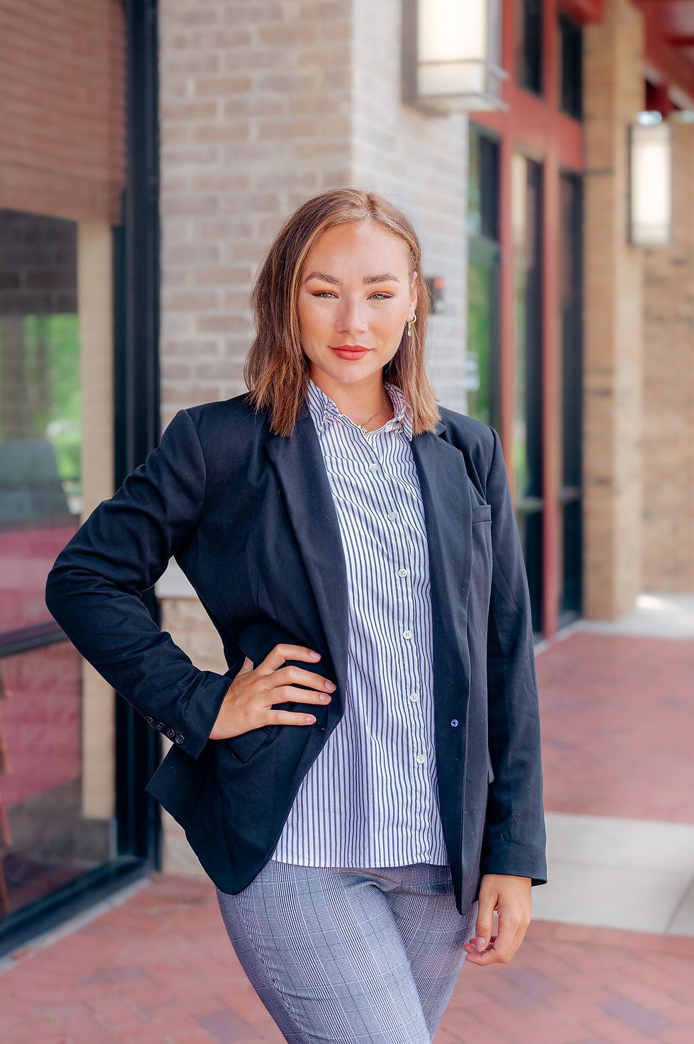 Woman in a black blazer and striped shirt stands confidently outside a brick building, hand on hip, with a slight smile.
10 Outfit Ideas for Women to Elevate Their Headshots