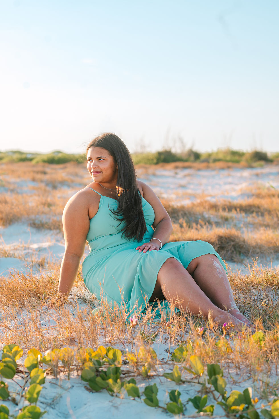 High school senior standing on the shoreline at Fort De Soto Beach during golden hour senior portrait session with a Tampa senior photographer, soft sunset light reflecting on the water.
