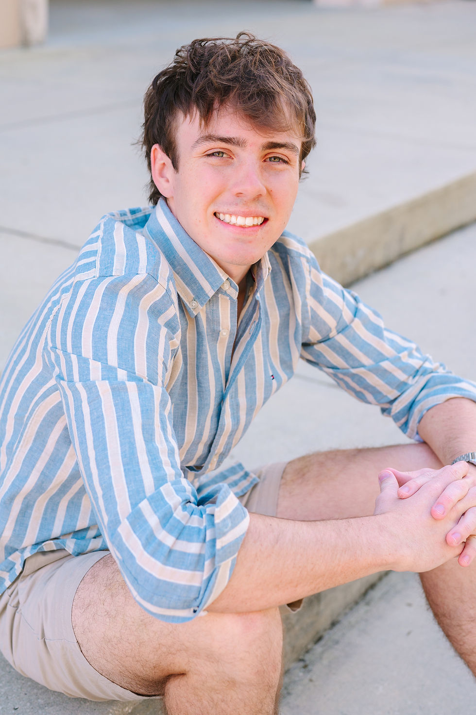 Senior boy sitting on the steps at St. Leo University, photographed by Tampa senior portrait photographer Nina Bashaw with a natural, relaxed expression and classic campus backdrop.