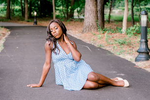 Senior girl sitting on tree lined pathway during portraits