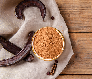 Dry carob pods and carob powder on linen napkin over wooden background
