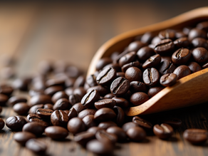 Roasted Coffee beans spilling from a wooden scoop onto a rustic wooden surface. Rich brown tones create a warm, inviting atmosphere. Starbucks Coffee Beans
