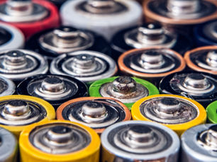 Close-up of a colorful assortment of lithium ion battery tops, featuring red, yellow, green, and silver hues. Batteries are closely packed together. for battery recycling.