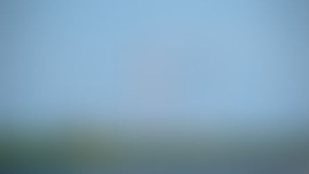 Wind turbine, red-striped smokestack, solar panels, and industrial buildings under a clear blue sky, showcasing renewable energy sources.