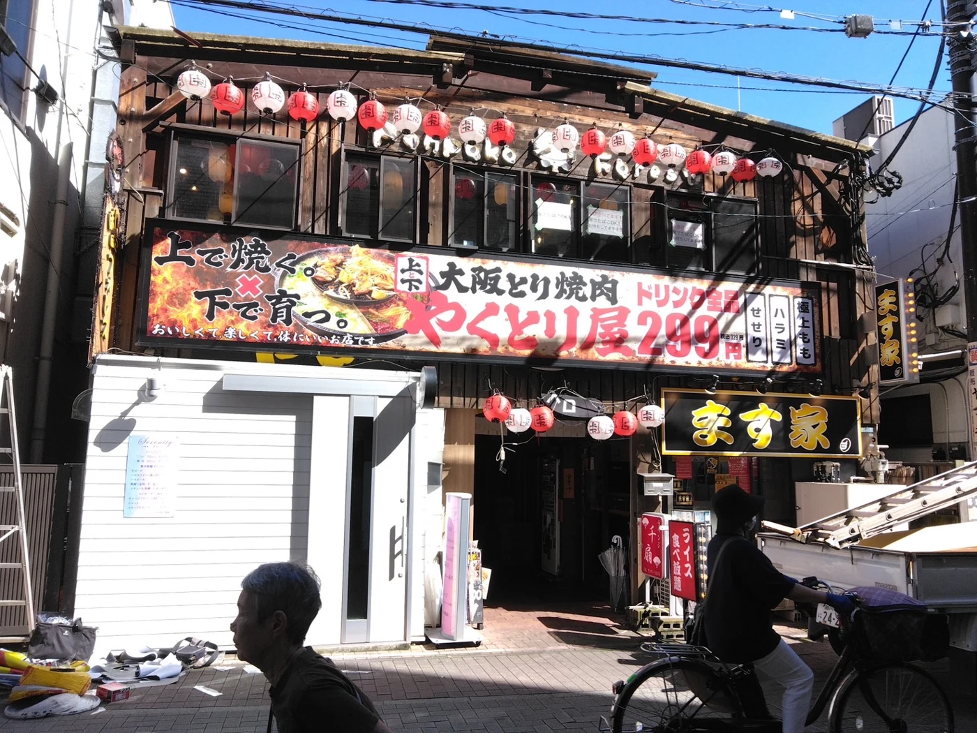 赤と白の提灯と、大阪とり焼肉 やくとり屋の看板が掲げられた草加店の外観
