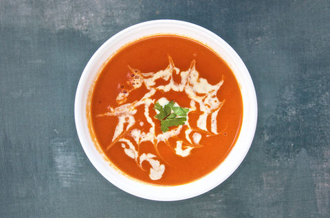 Bowl of tomato soup with cream swirl and herb garnish