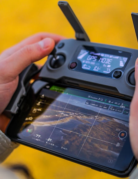 Close-up of hands operating a drone remote controller with live camera feed
