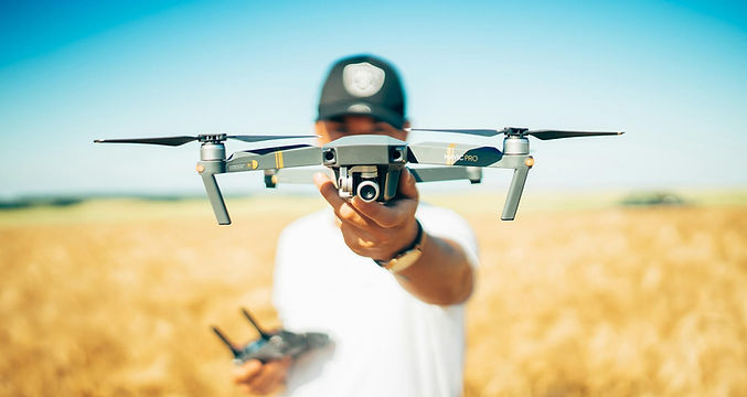 Drone pilot holding a drone outdoors in a golden wheat field