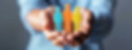 Hands hold three colorful cutout figures: blue, orange, yellow. Blurred blue background suggests a supportive, hopeful mood.