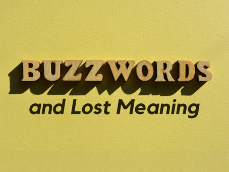 Wooden BUZZWORDS letters on a yellow background with shadowed text and Lost Meaning, like a simple book cover.
