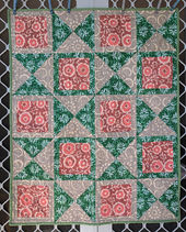 A baby quilt made with three fabrics. Fabrics are pink, green, and grey. Fabrics featured in the quilt are Indian batiks.