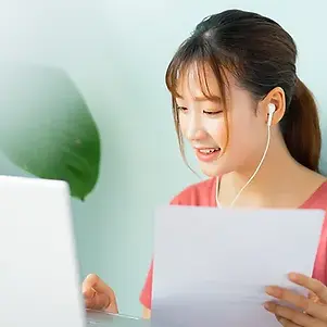 Asian woman wearing earphones while working at home.webp