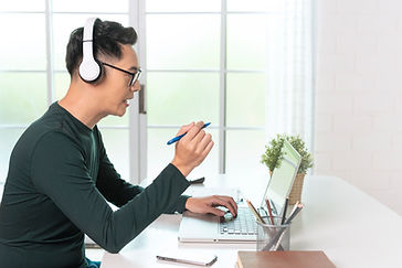 smiling-handsome-asian-businessman-wear-headphones-working-remotely-from-home-he-is-webina