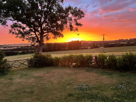 Vibrant orange sunset over rolling green fields and rural landscape at Frythens Cottages near Hayle, St Ives and Marazion in West Cornwall.