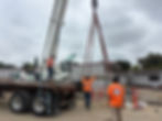 Workers offloading equipment from truck using crane