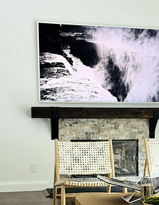 Frame-style TV displaying art above a stone fireplace in East Hampton