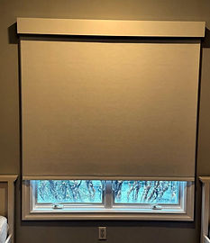 Motorized roller shade lowered over a window in an East Hampton home
