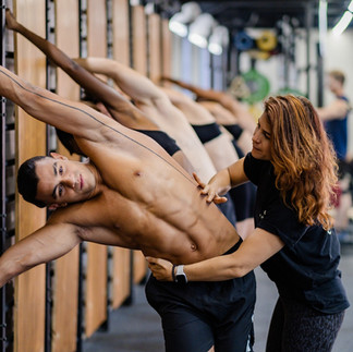 Instructor assisting a man with a side stretch in a fitness studio
