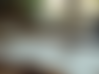 Desk with coffee cup/saucer and laptop in background. Wire bound note book with black pen sitting on notebook.