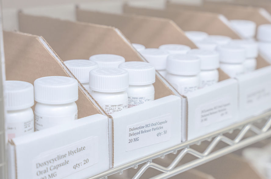 Labeled prescription medication bottles stored in organized inventory bins at an A-S Medication Solutions pharmacy facility,