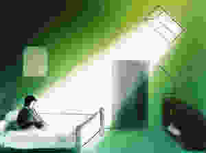 Anxious, depressed figure sits on bed bathed in light from a window
