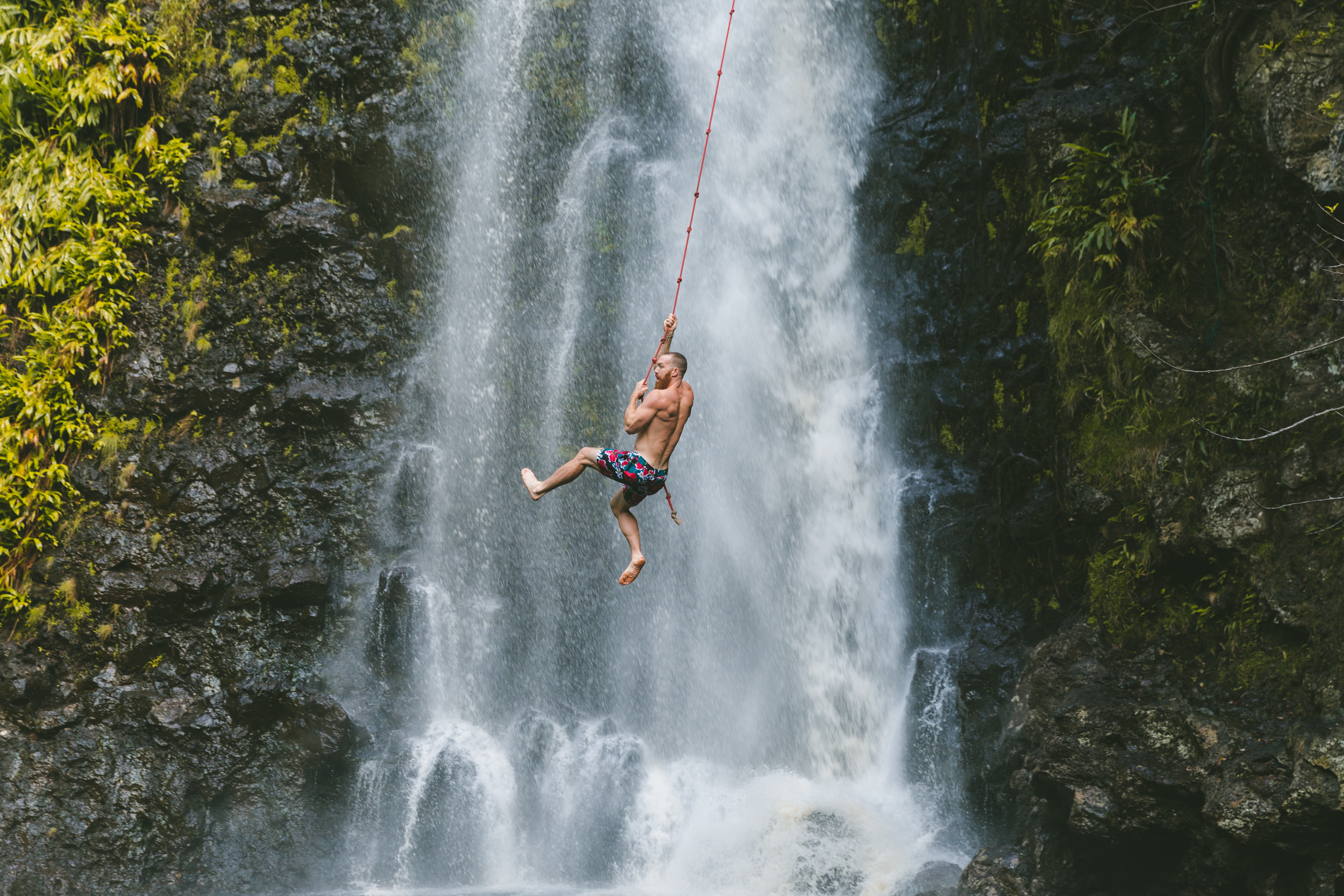 Boy hanging on a waterfall representing the YOLO mentality