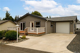 A small single-story grey home with a front-porch and an attached garage on the left side 