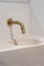 Gouden wandkraan boven een Solid Surface wastafel