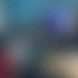 Students in a classroom with blue walls facing towards three men at the front of the classroom. A screen with the men's faces and names are visible.