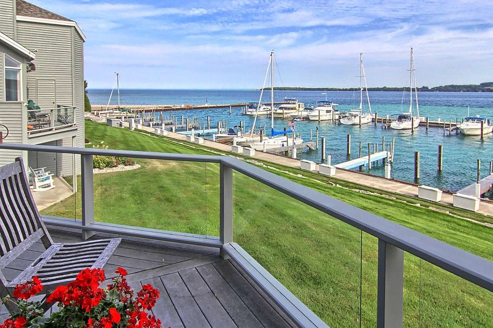 View of the Suttons Bay Yacht Club from a condo with a deck and green grass.