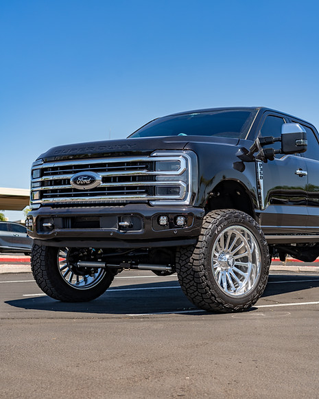 Front end of a custom Ford F-350 showcasing Baja Designs fog lights, lifted stance, and bl