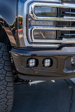 Front end of a custom Ford F-350 showcasing Baja Designs fog lights, lifted stance, and bl