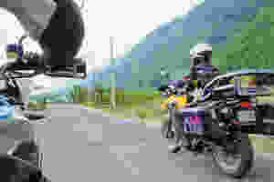 Woman with dog on motorcycle rides past another motorcycle