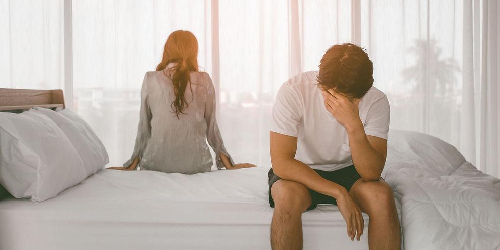 Couple sitting on opposite sides of the bed, having trouble in their relationship