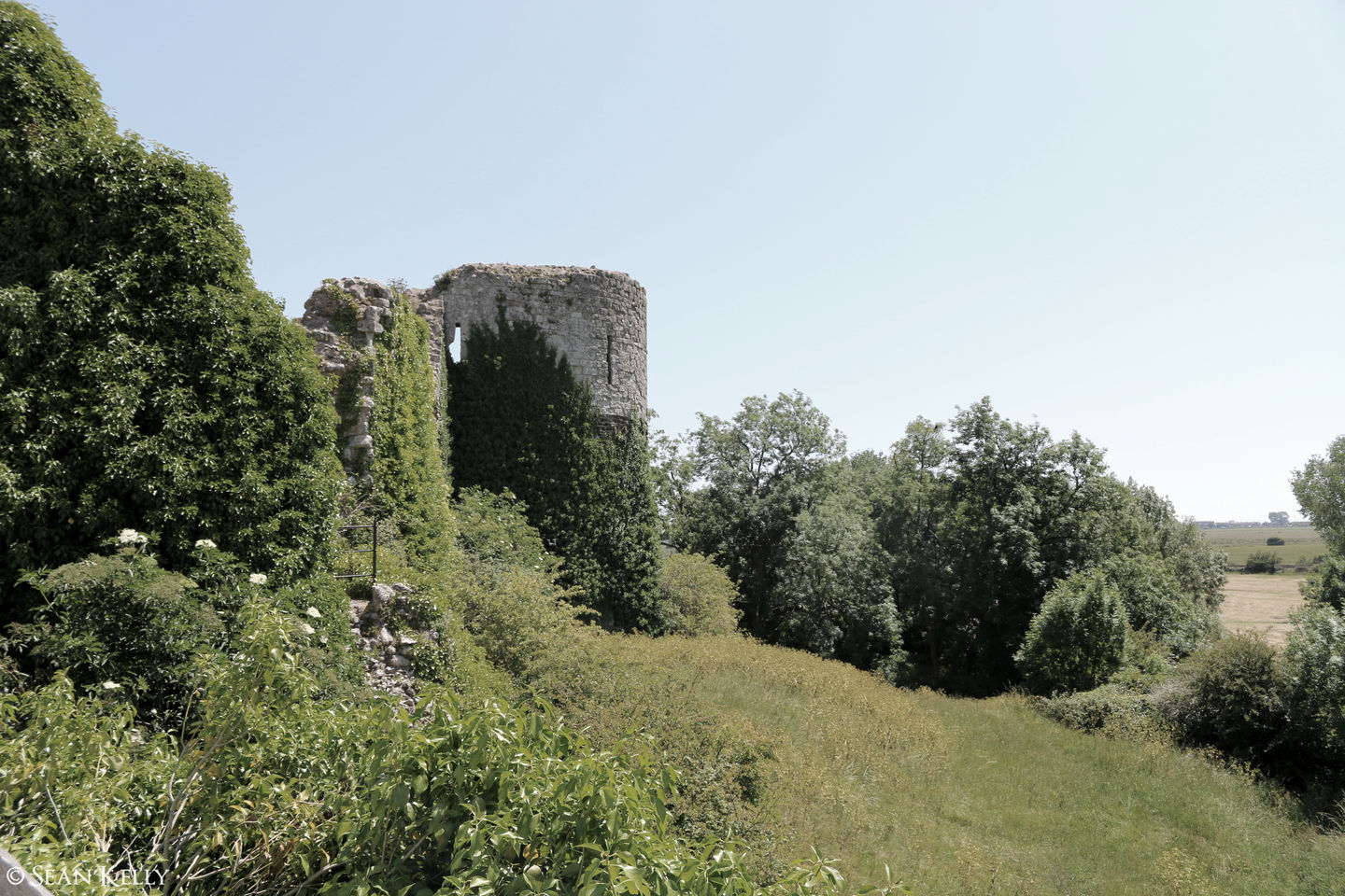 Photo of a turret at Pevensey Castle with surrounding countryside in summer