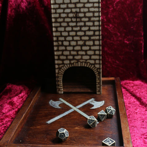 A wooden dice tower on a wooden dice tray with roleplaying dice on a red cloth background