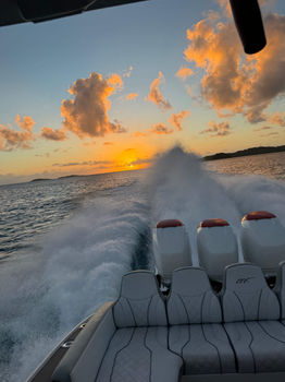 A boat speeding through water at sunset.