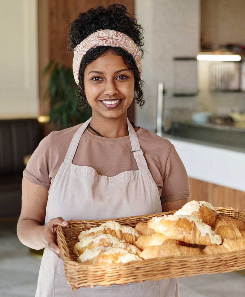 Smiling baker holding a wicker pan of freshly baked bread