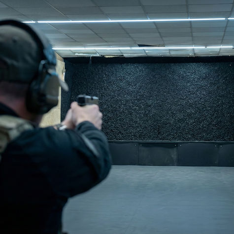 Modernisierter Indoor-Schießstand mit neuem, staubfreiem Granulat-Kugelfang-System im Hintergrund, Schütze in taktischer Ausrüstung beim Training auf kurze Distanz.