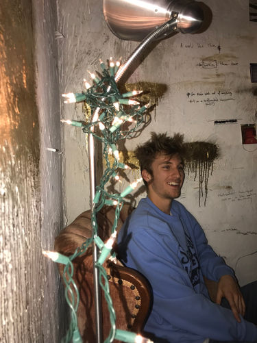 boy, string lights, writing on wall, gold paint, college
