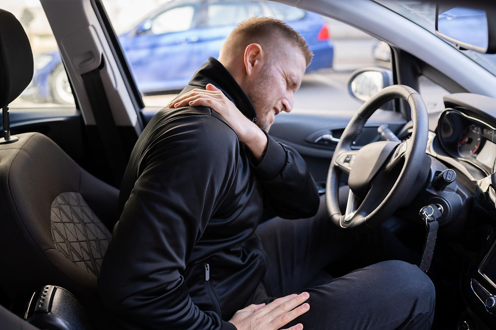 Man sitting in a car, clutching his shoulder in pain