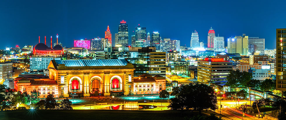 Night cityscape with brightly lit historic building in foreground, modern skyscrapers in background. Vibrant colors and clear sky.