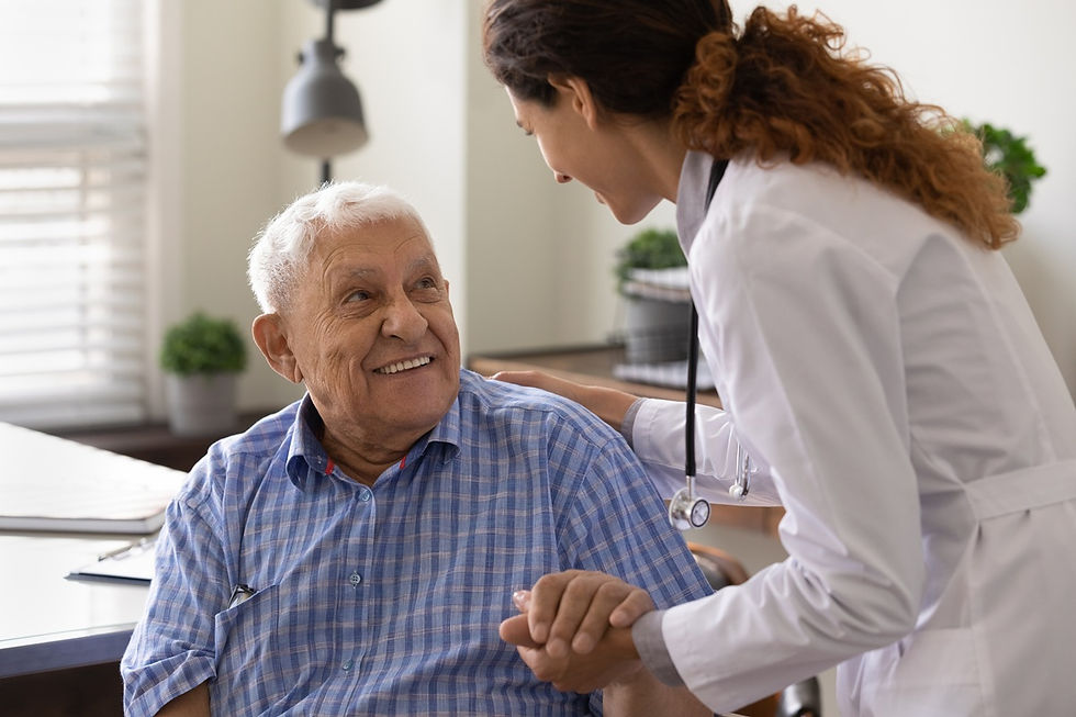 Female doctor comforts smiling elderly man in a bright clinic, holding his hand and shoulder during a checkup.