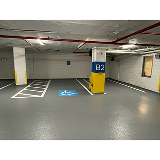 Renovated parking garage with fresh floor coatings, painted columns, ADA accessible parking space and pavement markings.