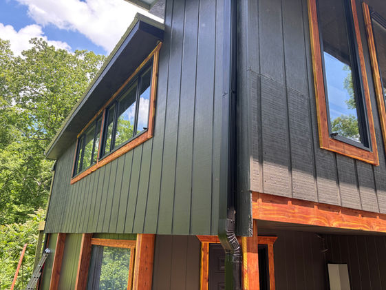 Side view of completed home exterior featuring dark paint and stained wood accents.