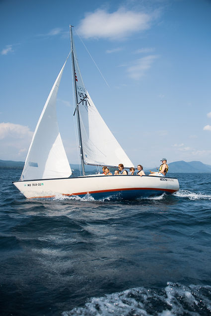 group of teens sailing a large boat on Lake George on a sunny day