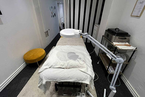 Et behandlingsrum, sandsynligvis brugt til spa- eller medicinske formål. Rummet har en behandlingsseng dækket med hvide lagne