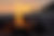 A bonfire dances on a beach at sunset.