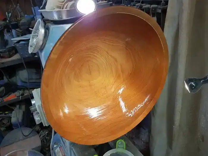 Applying oil finish to the inside of a hand-turned wooden bowl on the lathe