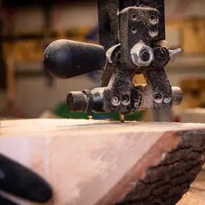 Close-up of a bandsaw cutting an ash woodturning blank, showing an early stage of safe workshop preparation.